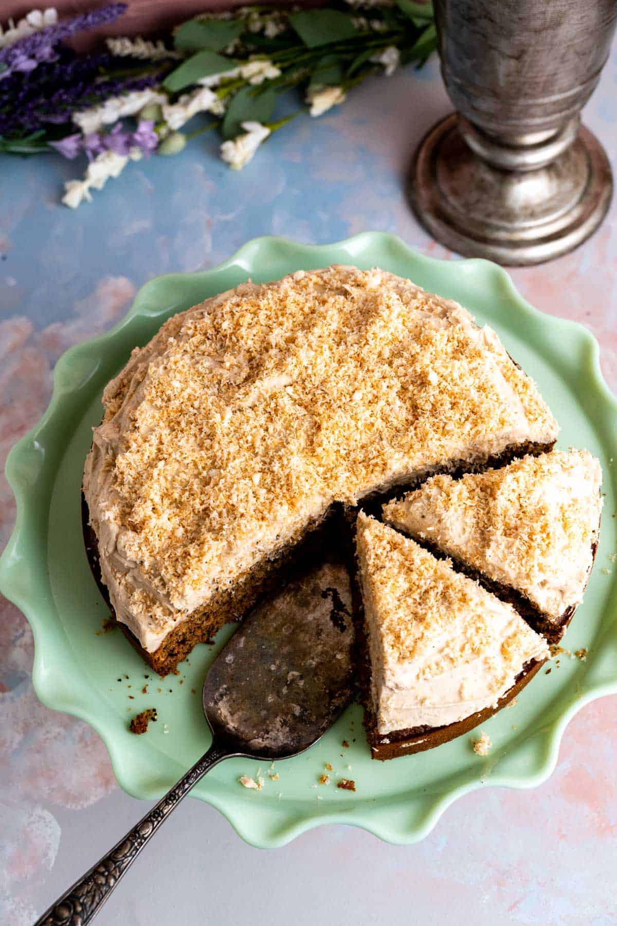 Over the head shot of coconut coffee cake with cut slices on the cake plate. 