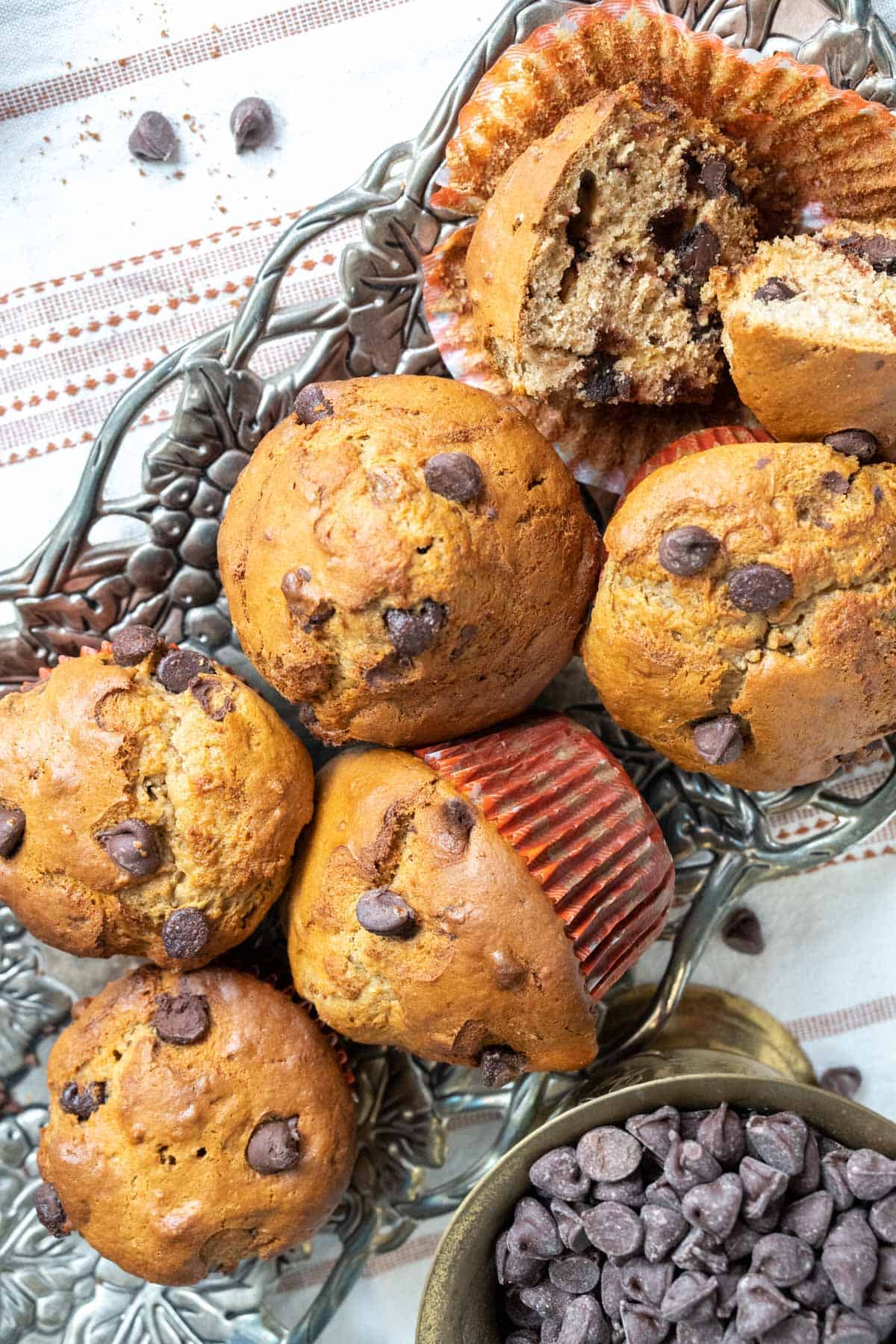 close up shot of chocolate chip banana muffins along with a bowl filled with chocolate chips. 
