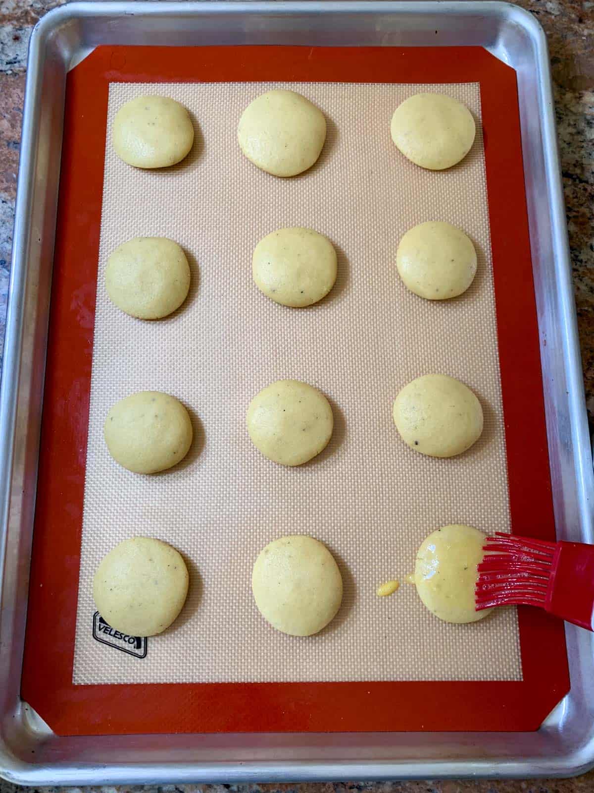 application of egg wash on the nankhatai cookies set in the baking tray.