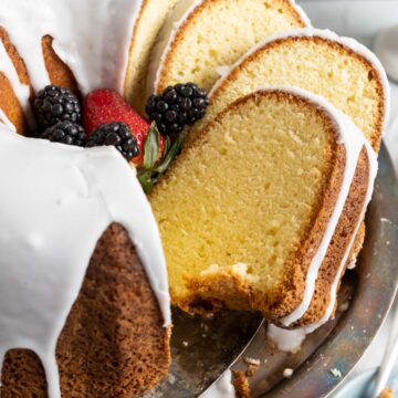 old fashioned sour cream pound cake with icing slices in a cake plate with golden spoon.