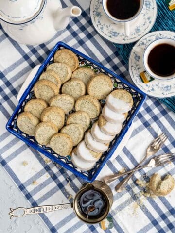 over the head shot of the shortbread cookies with tea cups and cookies in the deep blue dish.
