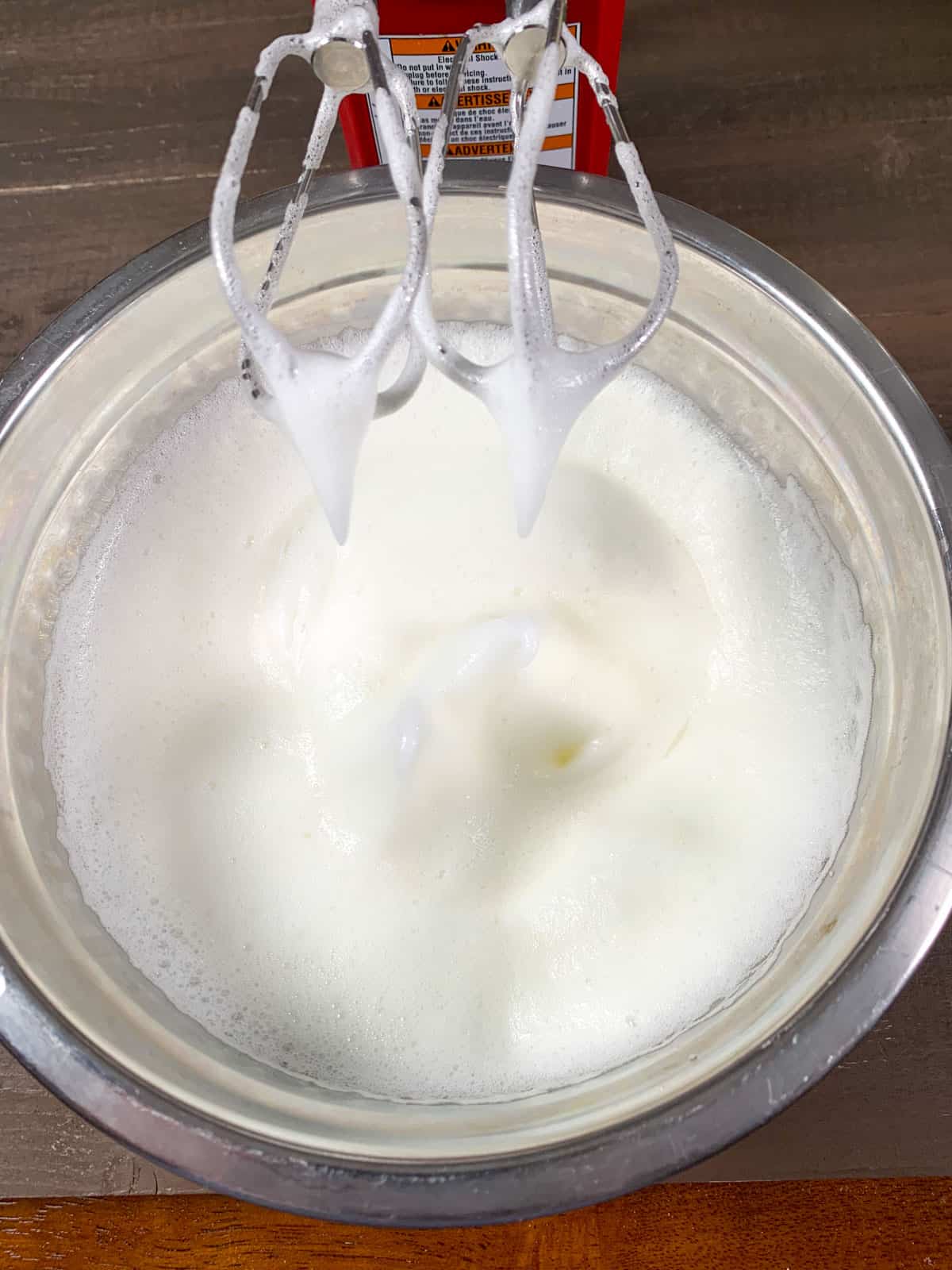 Soft peaks of egg whites beaten in a bowl.
