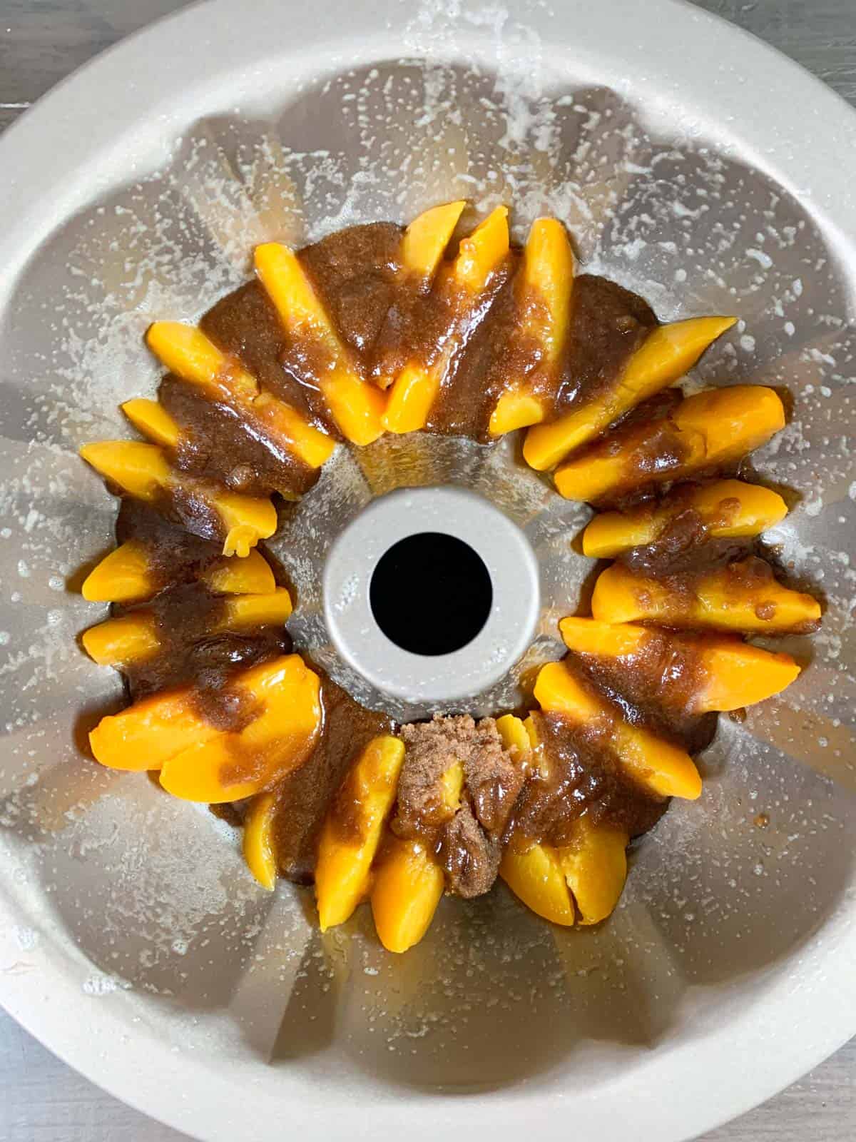 bundt cake pan with peaches in the bottom with brown sugar mixtures on it. 