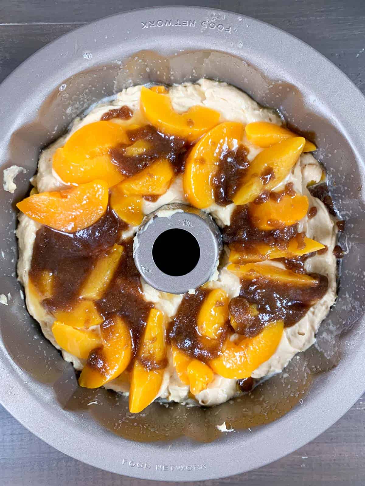 placing peaches pieces on a layer of peach cobbler pound cake batter.