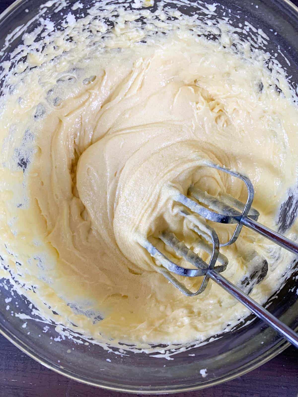 Mixing eggs and vanilla to butter and sugar mixture for pinwheel cookies.
