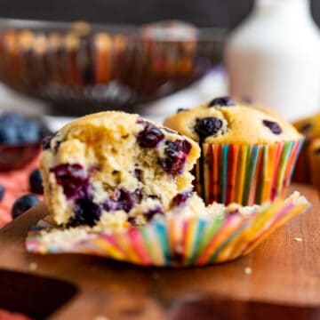 half opened old-fashioned blueberry muffins showing the texture and placed on the wooden plank.