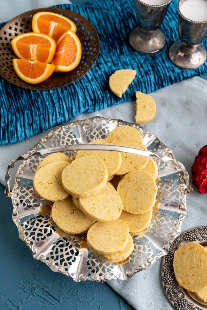 orange shortbread cookies in a fancy silver dish on the table.