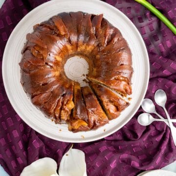 overhead shot of peach cobbler pound cake in a white cake tray with lily flowers around.