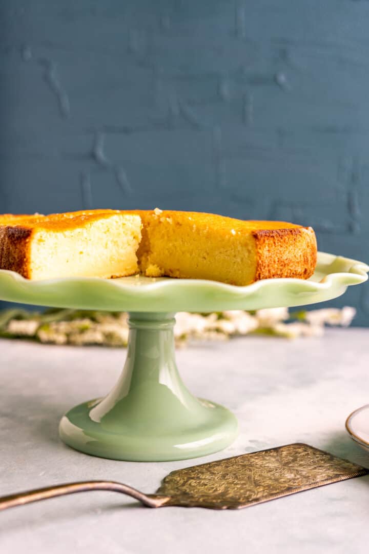close shot of the butter cake in a green cake plate with a golden cake spoon sitting on the table.