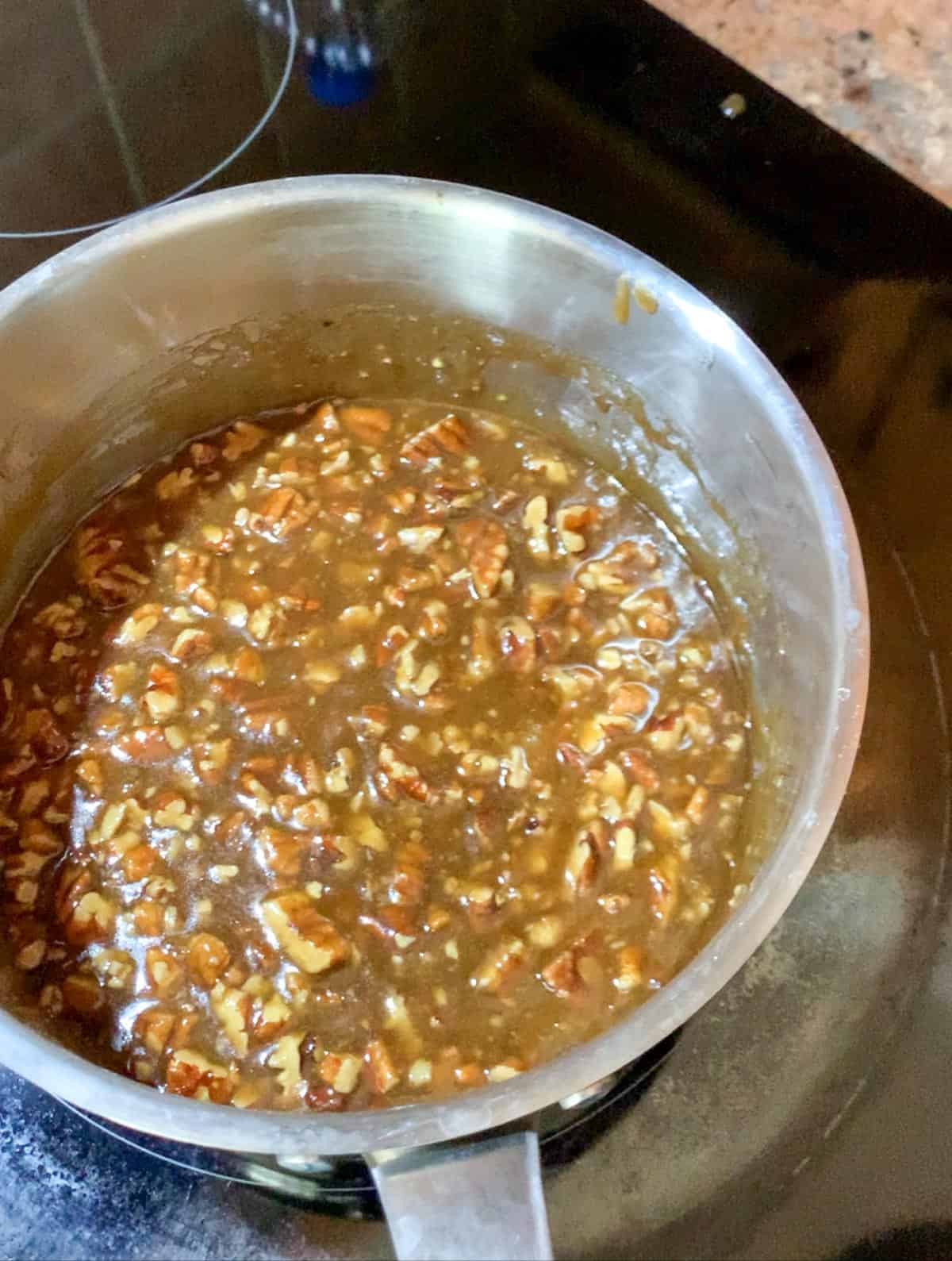 pecan sauce in a the saucepan on the stove for pecan cake.