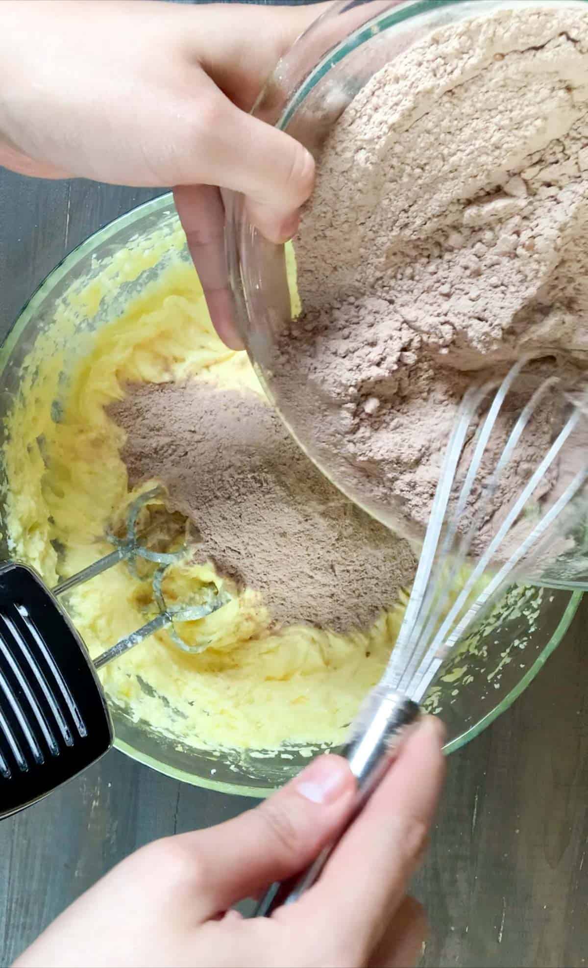 adding the dry ingredients into the wet ingredients of the chocolate cake batter.