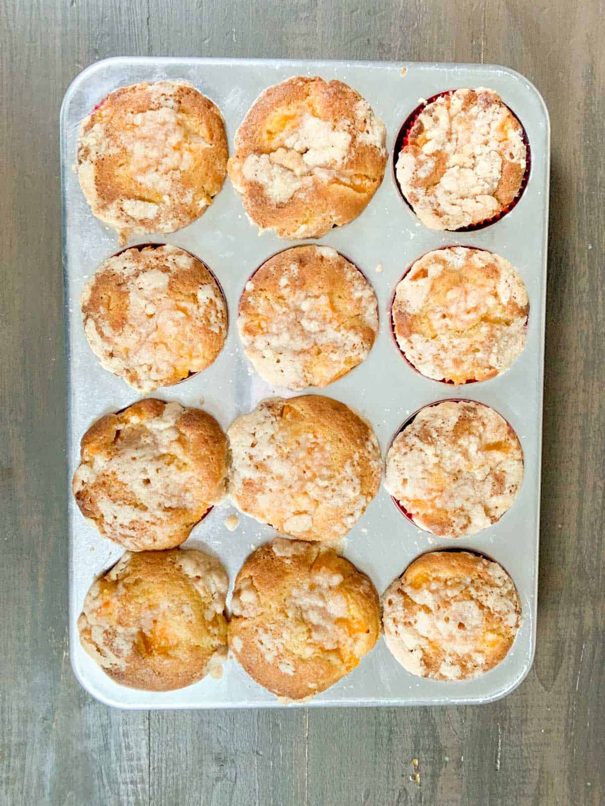 baked peach cobbler muffins in the muffin tray.