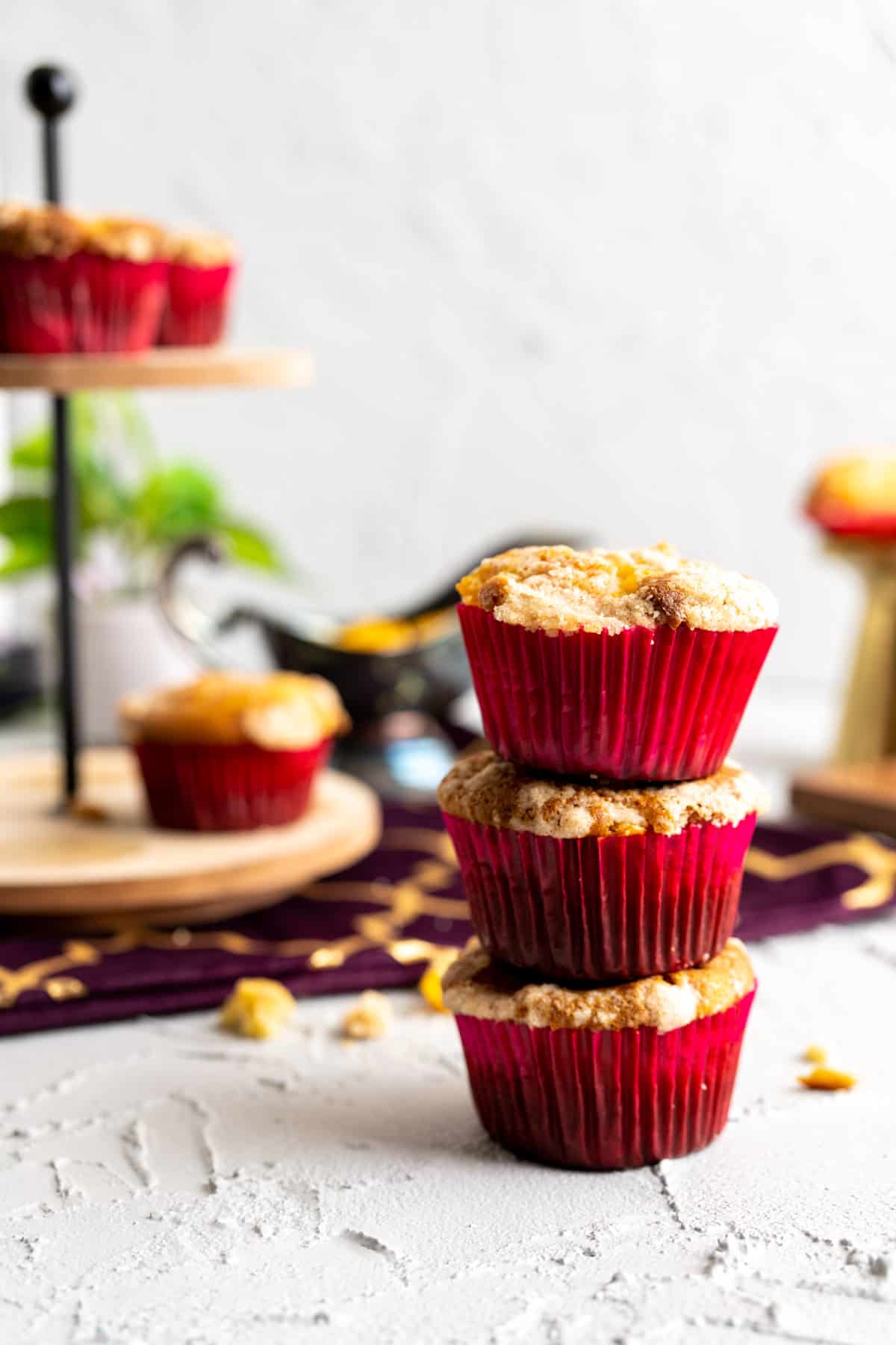 peach cobbler muffins stacked together and a cake stand in the backdrop with more muffins.