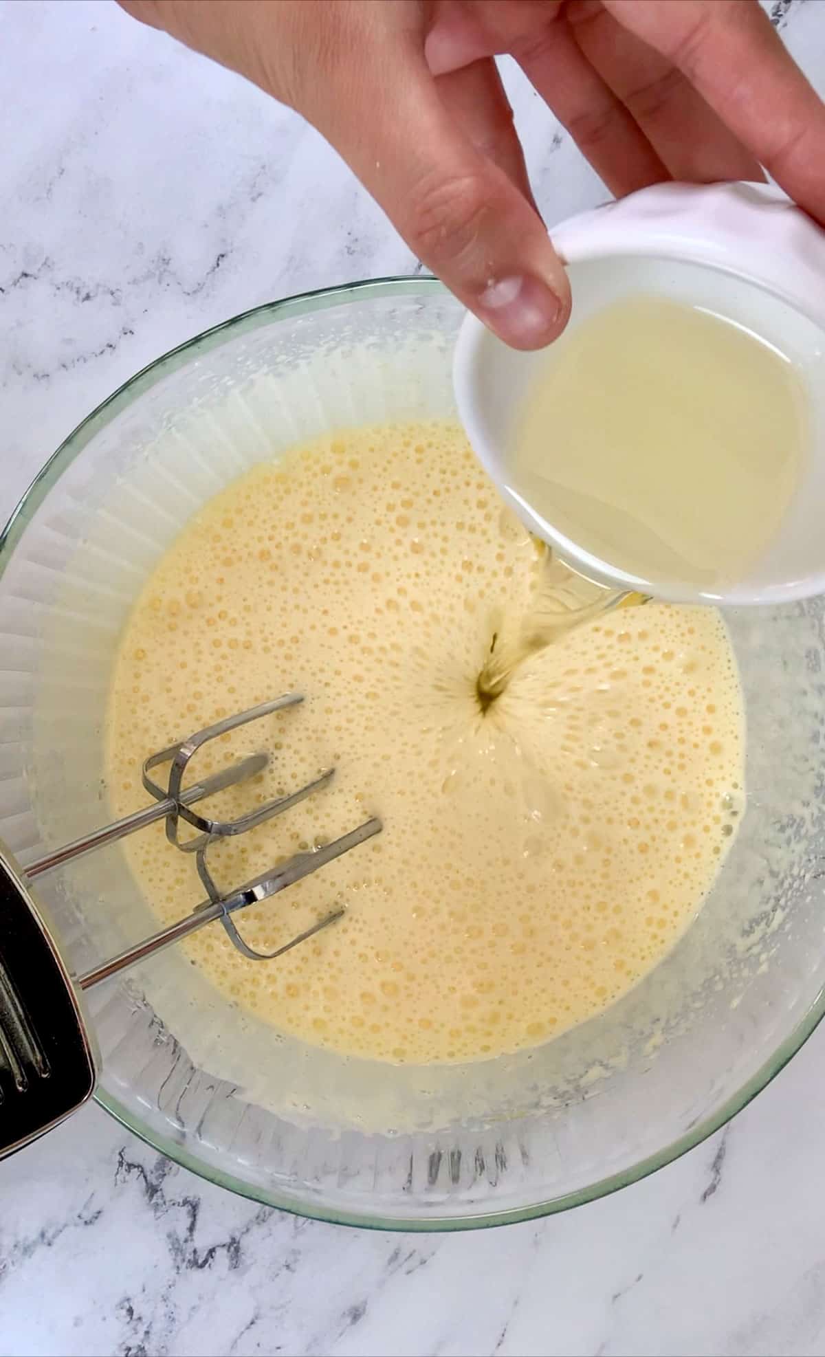 adding the oil in the beaten eggs and sugar mixture for italian almond cake recipe.