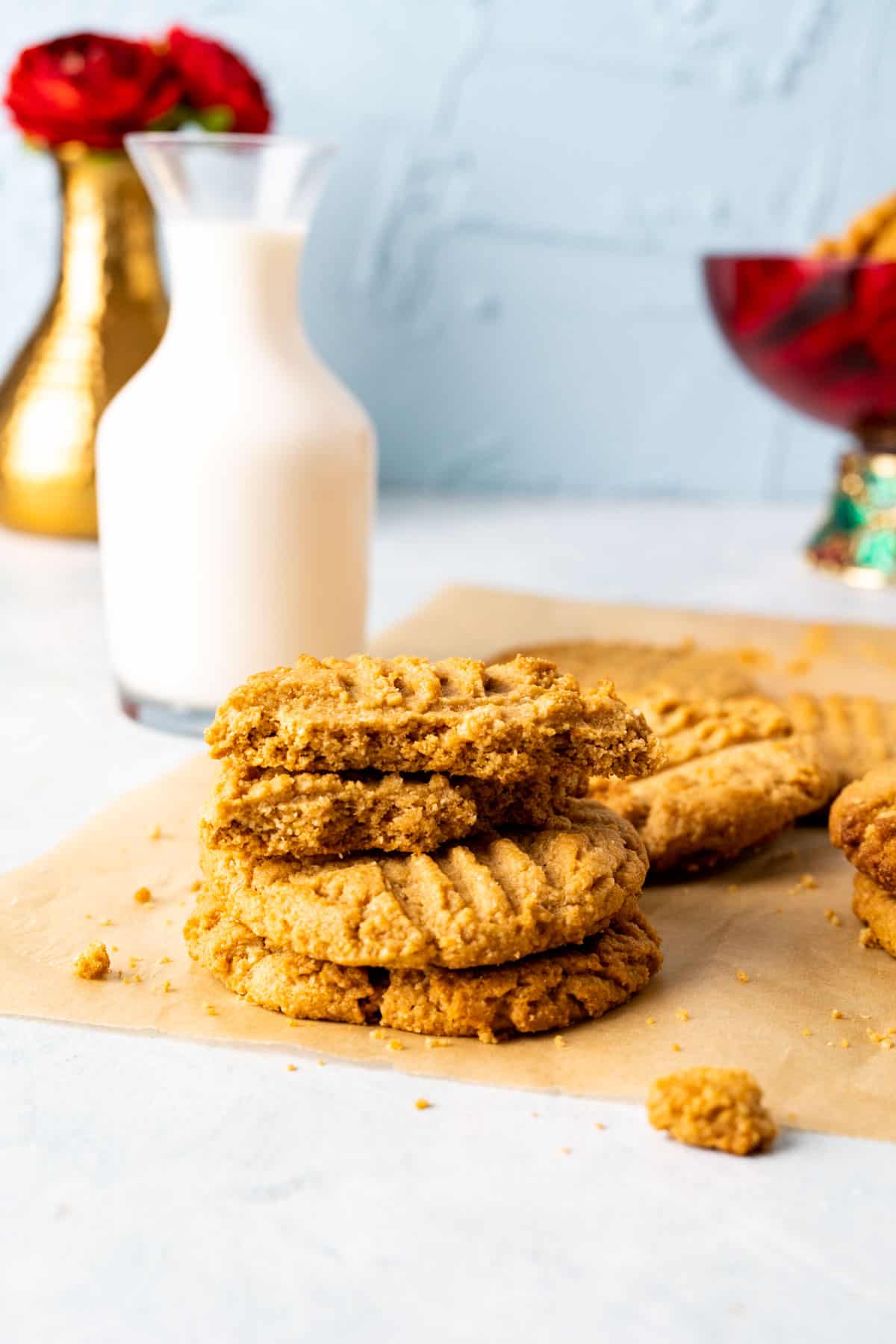 three almond flour peanut butter cookies stacked over one another with milk bottle in the backdrop.