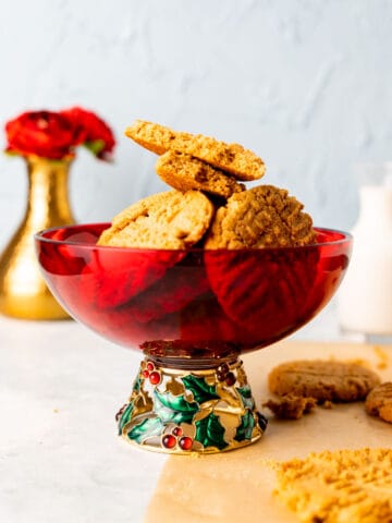 almond flour peanut butter cookies placed in a decorative red bowl with golden vase in the backdrop.