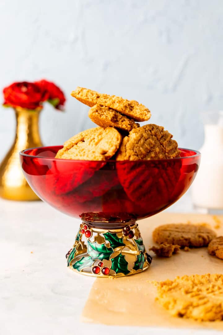 almond flour peanut butter cookies placed in a decorative red bowl with golden vase in the backdrop.