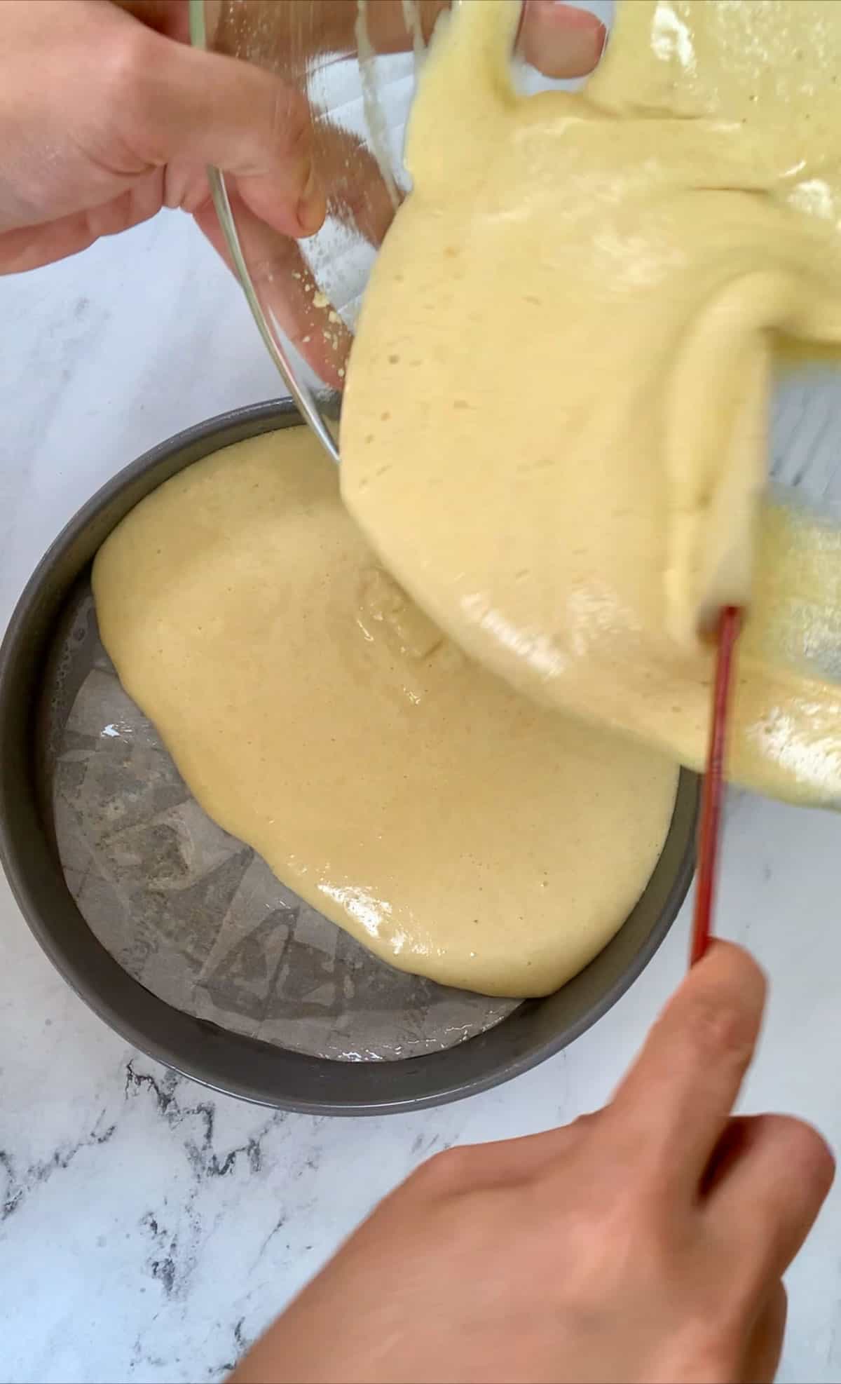 Pouring the italian almond cake batter into the greased pan. 