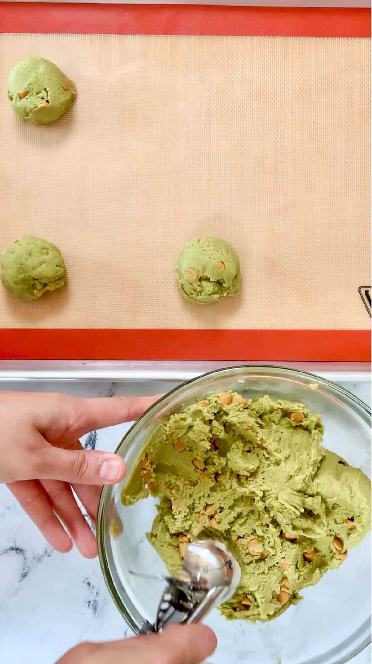 scooped out matcha cookies placed on the silicone sheet on a baking tray.