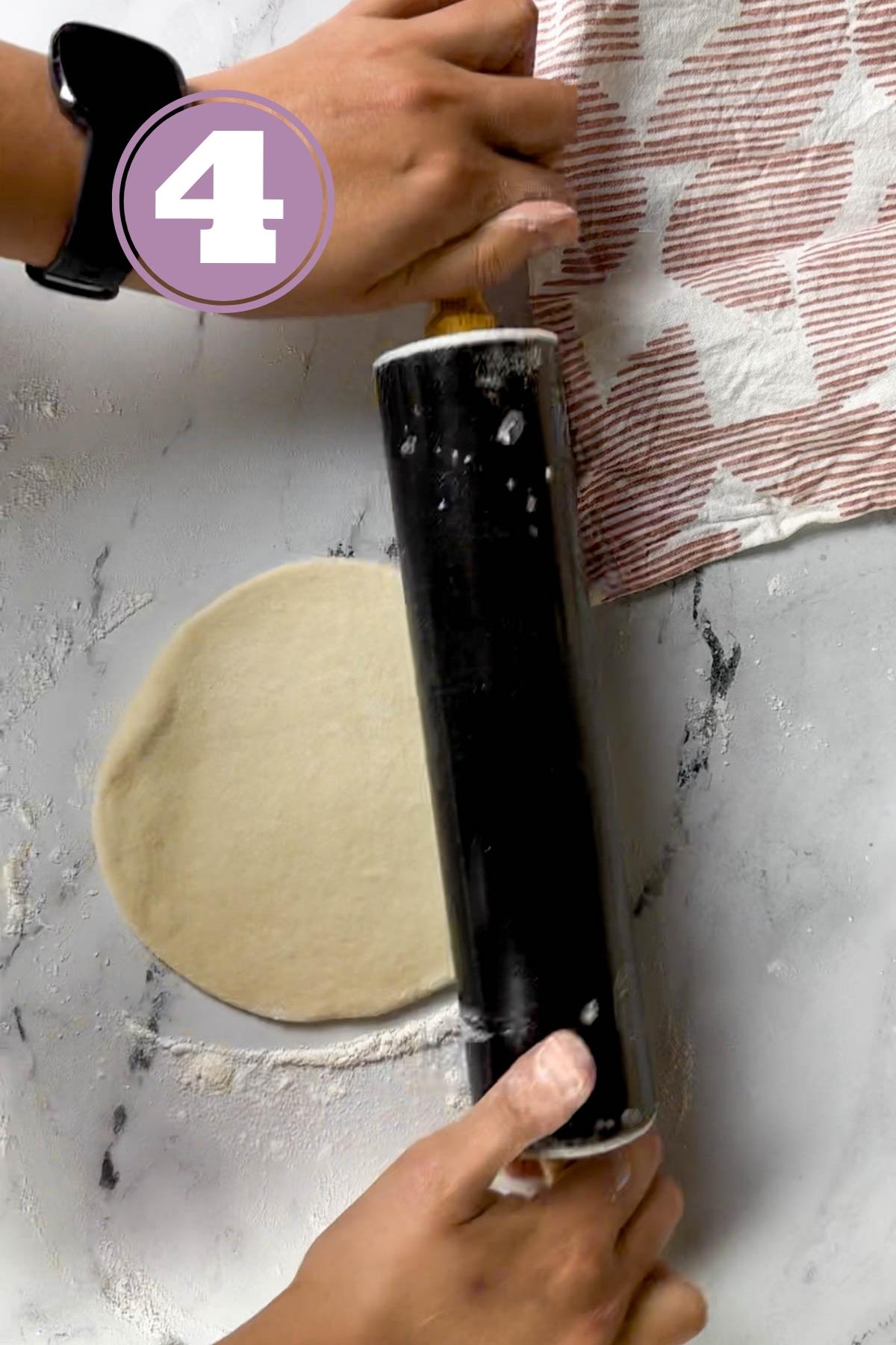 Overhead shot of rolling out a turkish bread loaf with a rolling pin.