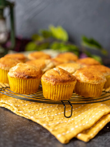 close shot of bisquick banana muffins placed on a black round-shaped wire rack on a yellow table cloth.