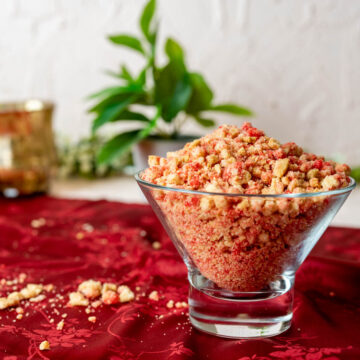 strawberry crunch topping in a transparent bowl placed on a red table cloth.