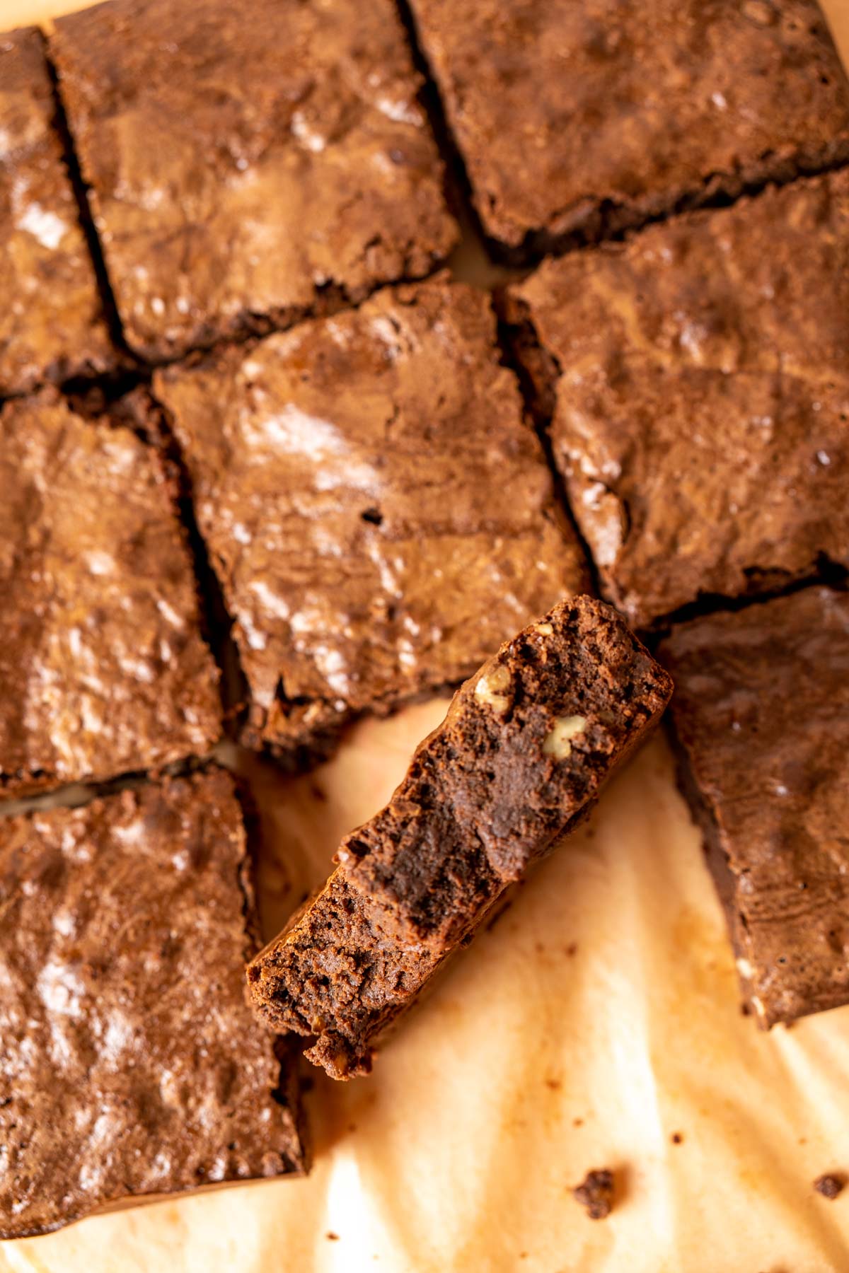 one condensed milk brownie standing among other brownies on brown paper.
