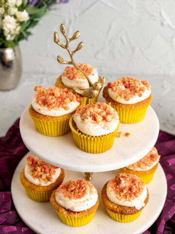 strawberry crunch cupcakes on a white cupcake stand with flowers in the backdrop.