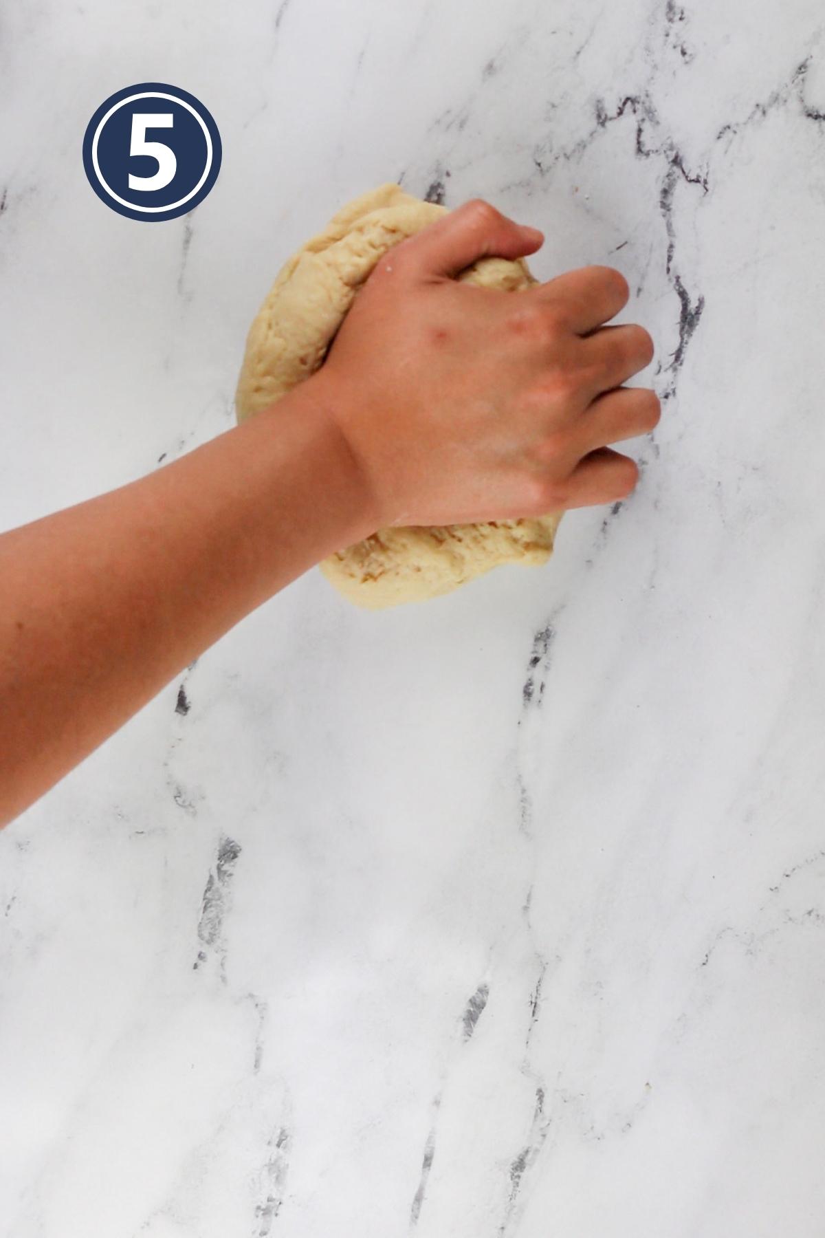 kneading the dough with hand on the counter.