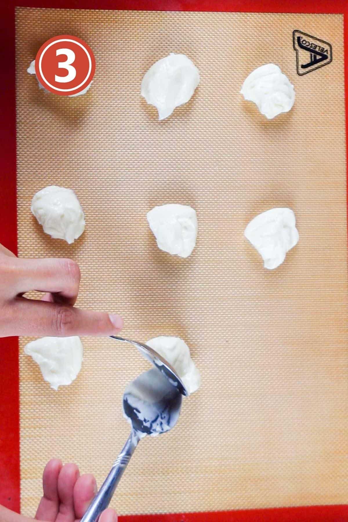 making cream cheese dollops using a spoon on a silicone sheet.