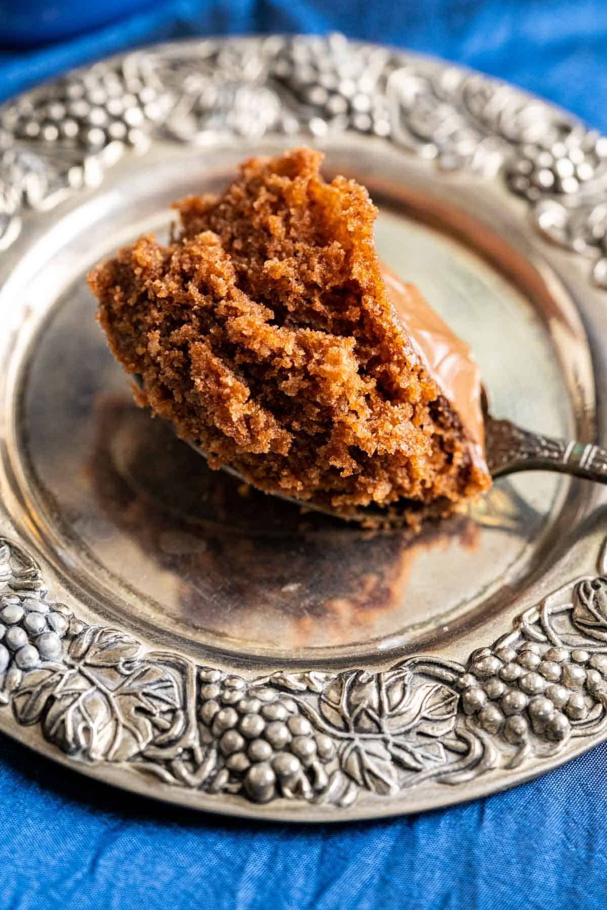 bite of nutella mug cake in a spoon placed in a silver antique plate.
