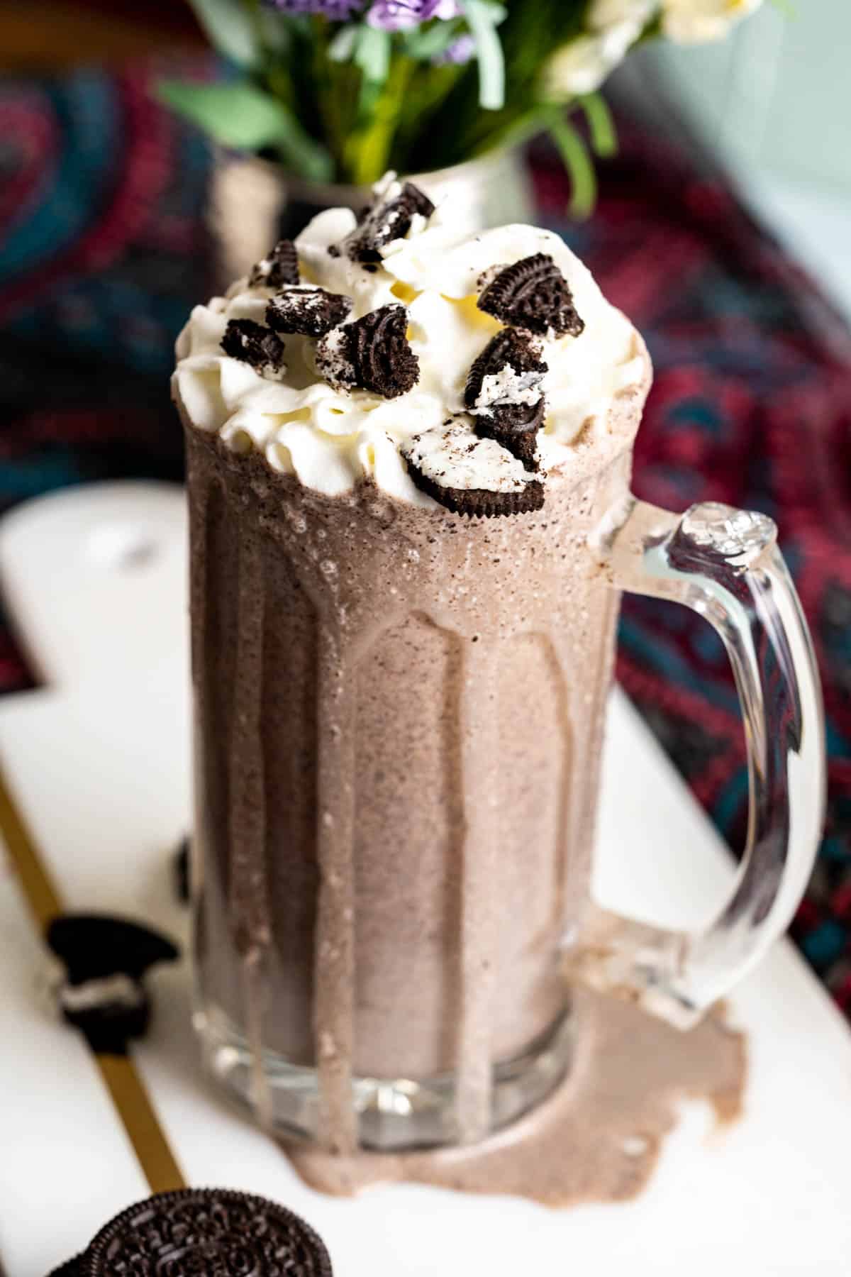 Oreo milkshake in a glass with dollop of whipped cream and crushed Oreos.