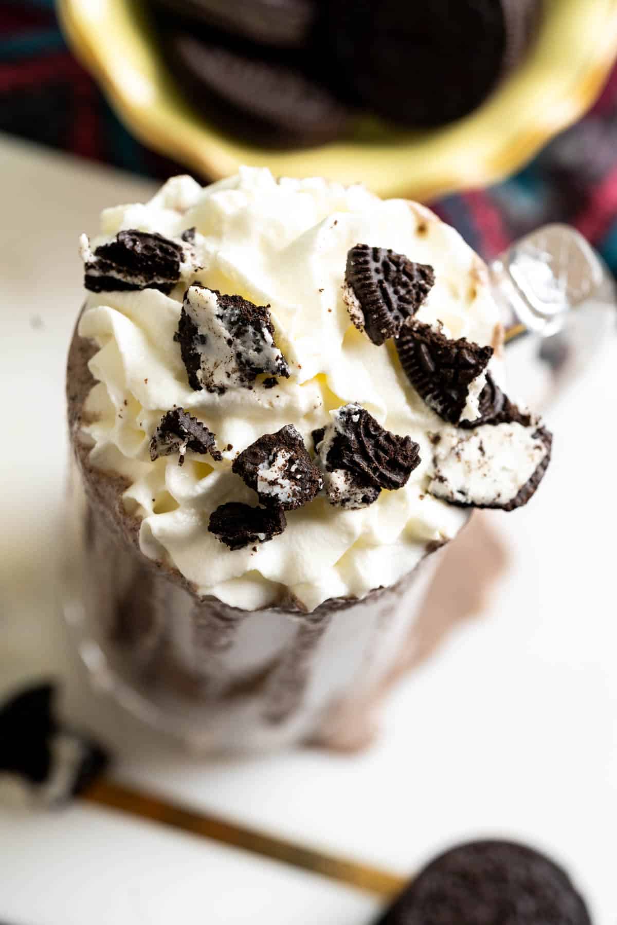 close shot of oreo shake in a tall glass on white marble plate.