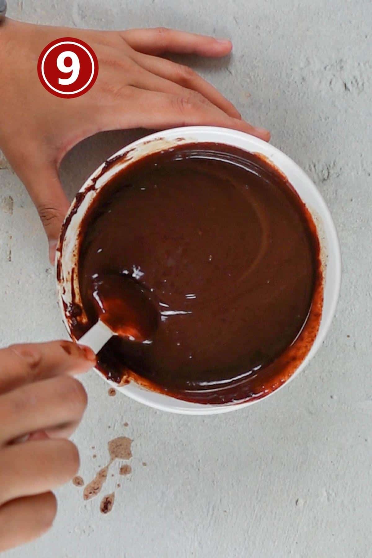 mixing the chocolate chips with heavy cream to make chocolate ganache in a white bowl.
