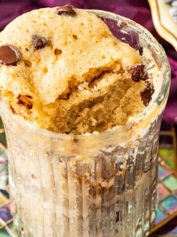 mug cake in a transparent mug with chocolate chips sprinkled on the top.